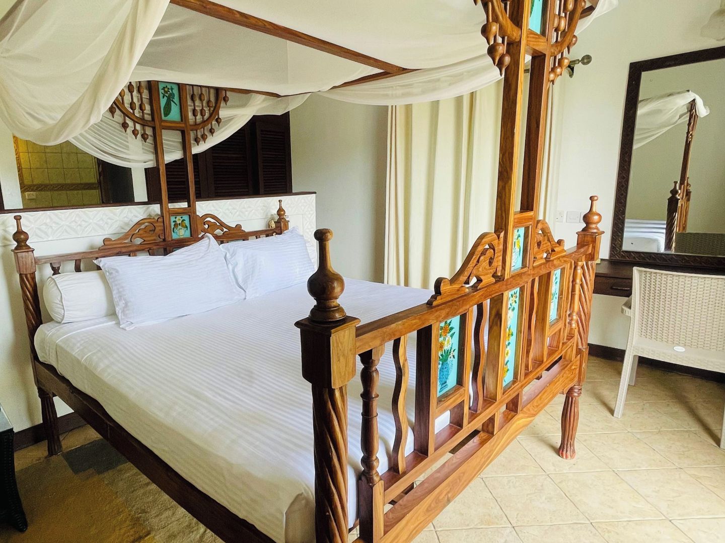 Una cama con dosel, cabecera de madera y cubrecama blanco.