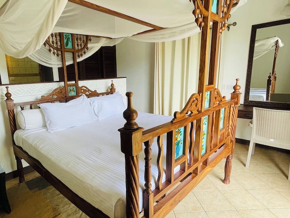 A four-poster bed with a canopy, a wooden headboard, and a white bedspread. - Mango Villa (Mtwapa)