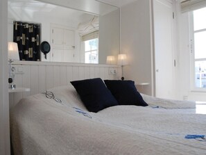 A bedroom with a large bed, two bedside lamps, a mirror, and a window. - Apartment in Nerja Near Carabeillo Beach (Nerja)