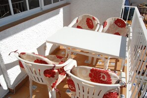 A white table and chairs with floral upholstery on a balcony with a white railing. - Apartment in Nerja Near Carabeillo Beach (Nerja)