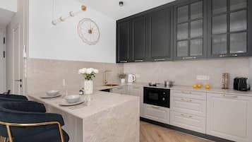Una cocina moderna con armarios blancos, una isla central y un comedor con sillas negras.