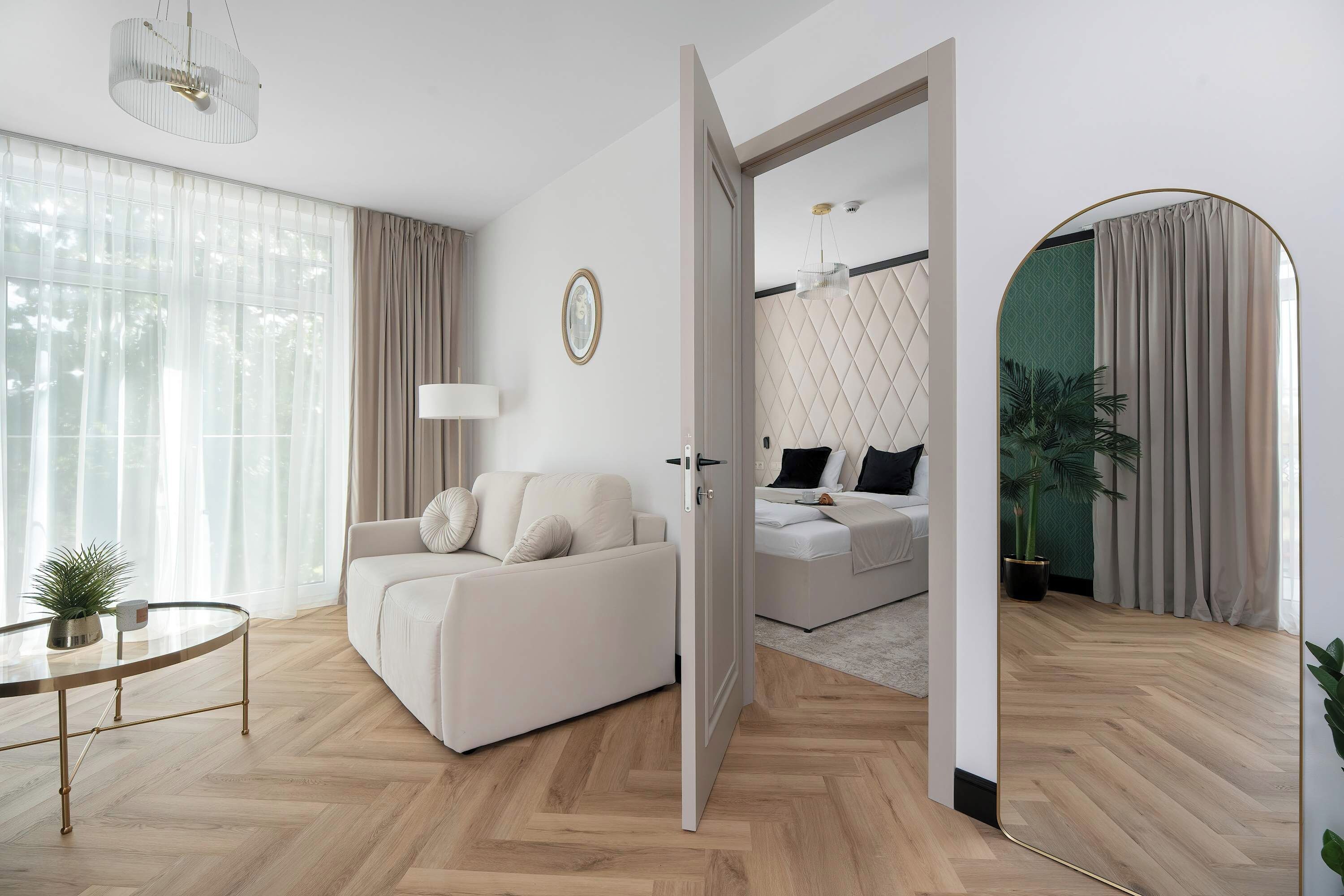 A modern living room with a sofa, a dining table, and a view into a bedroom.