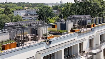 Ein modernes Gebäude mit mehreren Balkonen, Dachgärten und freiem Blick auf die umliegende Stadtlandschaft.