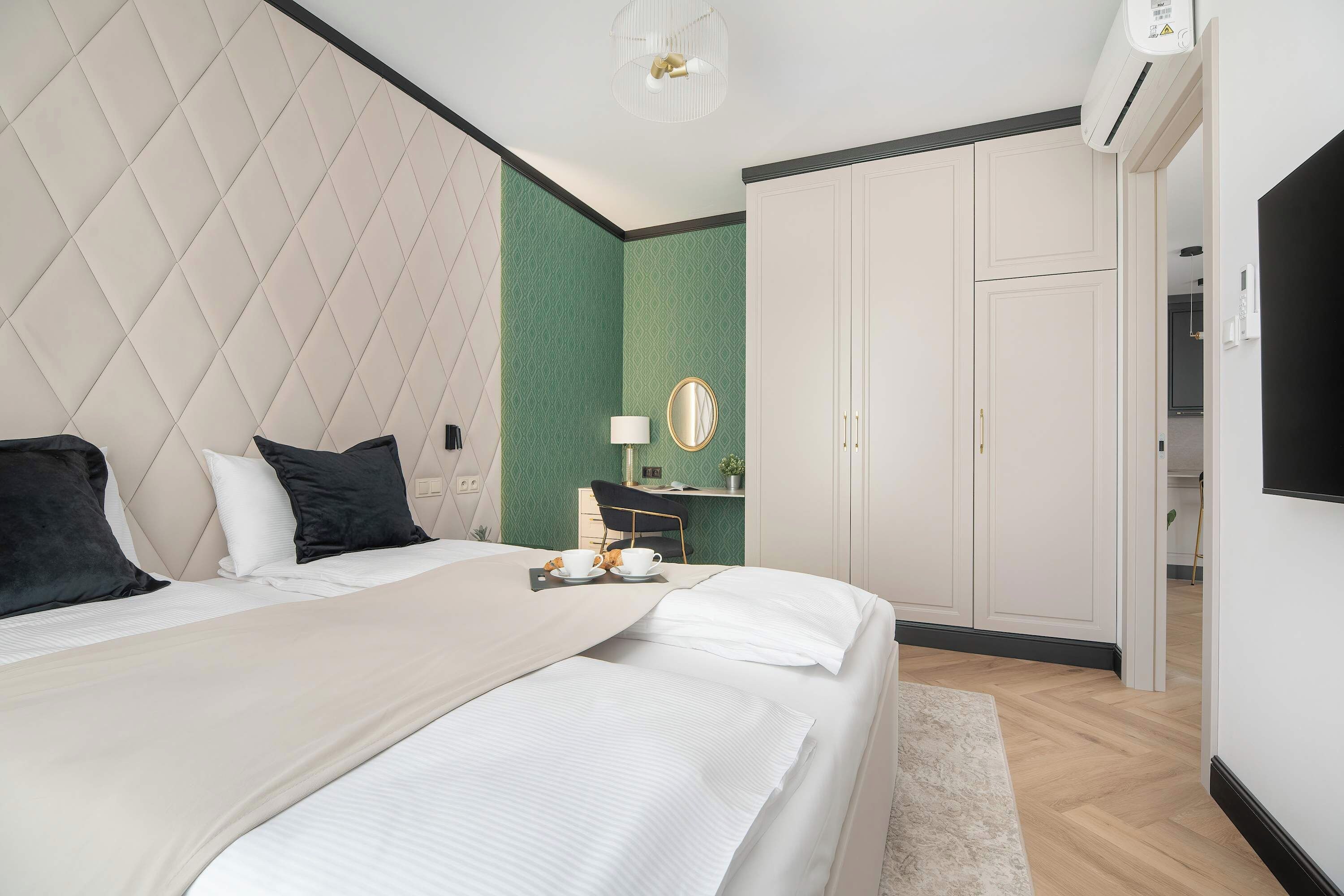 Habitación de hotel con una cama grande, un escritorio con silla, un armario y una televisión.