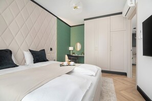 Ein Hotelzimmer mit einem großen Bett, einem Schreibtisch mit Stuhl, einem Kleiderschrank und einem Fernseher.