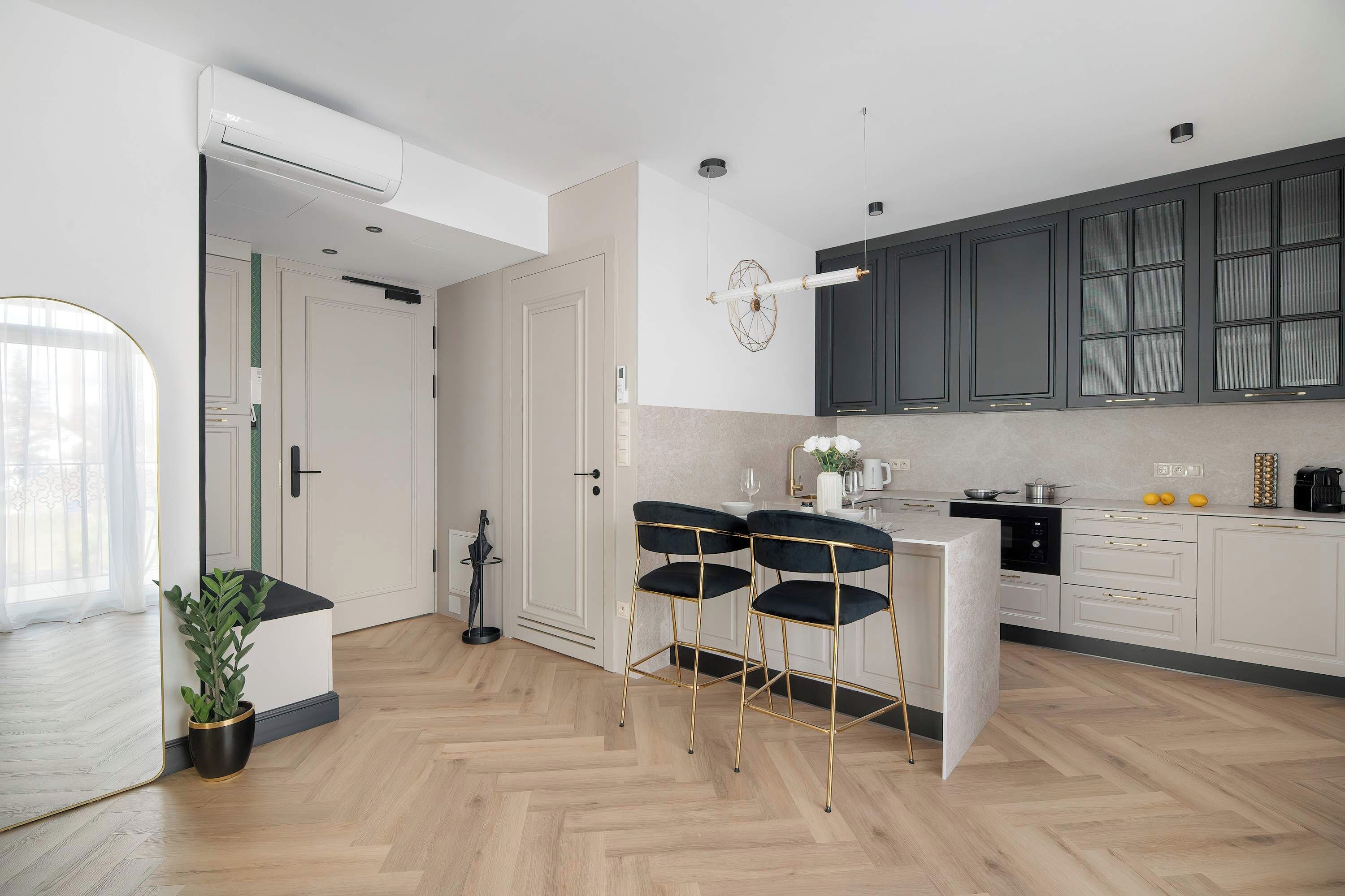 Una cocina moderna con piso de espiga, una isla central con taburetes de bar y vista al área de comedor.