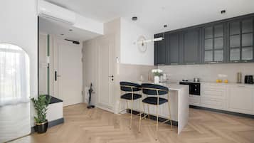 Una cocina moderna con piso de espiga, una isla central con taburetes de bar y vista al área de comedor.