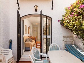 Eine Außenpatio mit Tisch und Stühlen, einer Couch und Blick in ein Zimmer mit Bett und Essbereich.