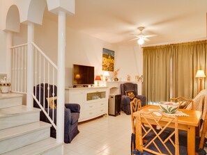 Ein Wohnzimmer mit Treppe, Essbereich und Fernseher.