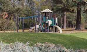 A playground with a slide and climbing structures, surrounded by trees and grass. - Oktoberfest & Marathon Weekend! 2BR WorldMark Resort (Leavenworth)