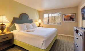 A hotel room with a bed, bedside lamps, a dresser, a window with blinds, and a framed picture on the wall. - Oktoberfest & Marathon Weekend! 2BR WorldMark Resort (Leavenworth)