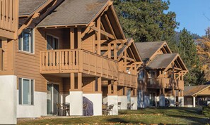 Une rangée de chalets en bois dotés de balcons, chacun comprenant un petit espace patio avec des chaises.