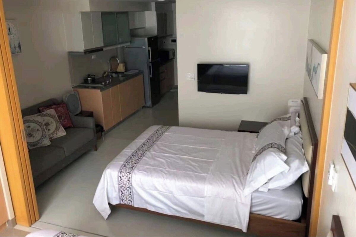 A compact bedroom with a bed, a small bedside table, and a wall-mounted TV.