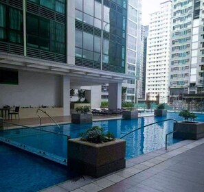 A rooftop pool area with clear blue water, surrounded by modern buildings and potted plants. - Elegant Urban Stay in Taguig City (Taguig)