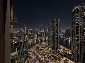 A nighttime cityscape with high-rise buildings, a river, and a well-lit waterfront area. - Peninsula Two - 3410 Studio (Dubai)