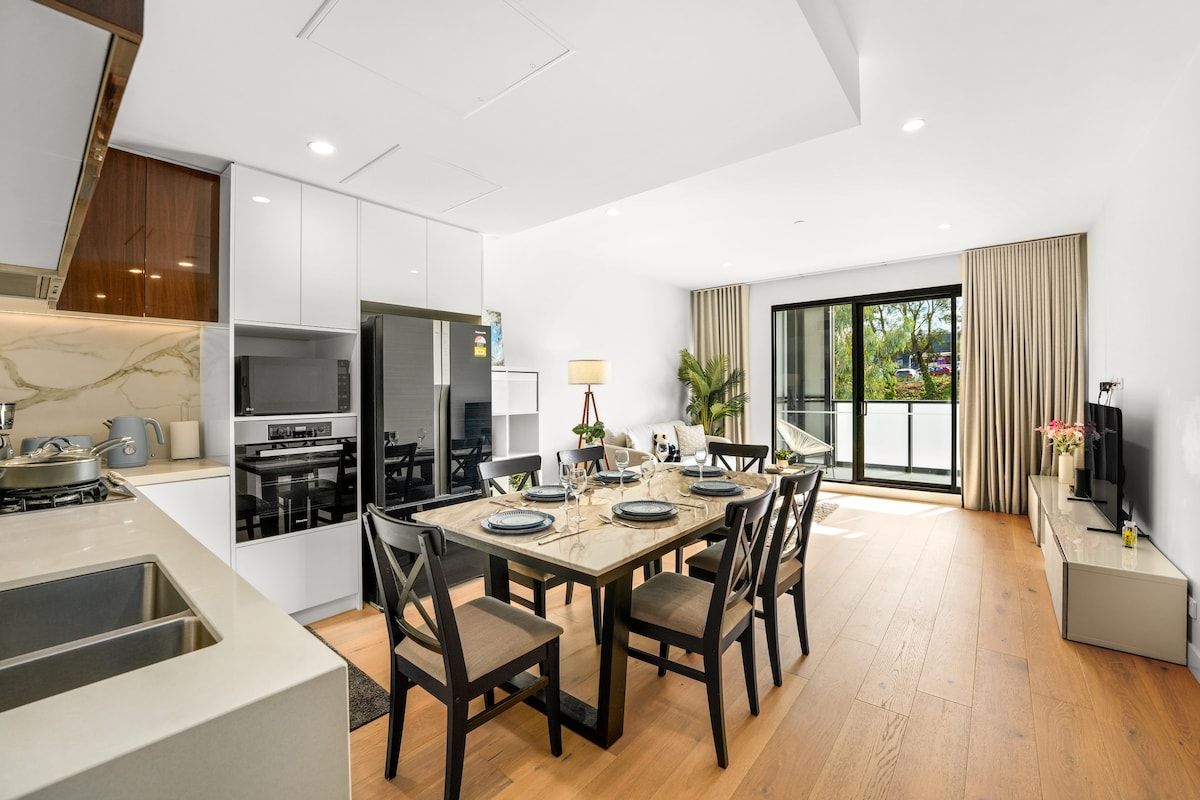 Una cocina moderna con comedor, televisor y un amplio ventanal.