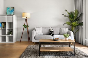 A modern living room with a sofa, a coffee table, a lamp, a bookshelf, and a potted plant. - Seednest Modern Apt by Mall, BBQ & Parking (Doncaster East)