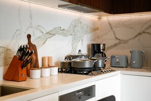 A kitchen with a marble backsplash, a stove, a coffee maker, and a toaster. - Seednest Modern Apt by Mall, BBQ & Parking (Doncaster East)