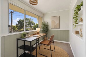 Ein Zimmer mit Schreibtisch, Stuhl und Blick auf Bäume.