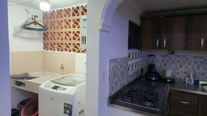 Una cocina compacta con lavadora, estufa a gas y salpicadero de azulejos.