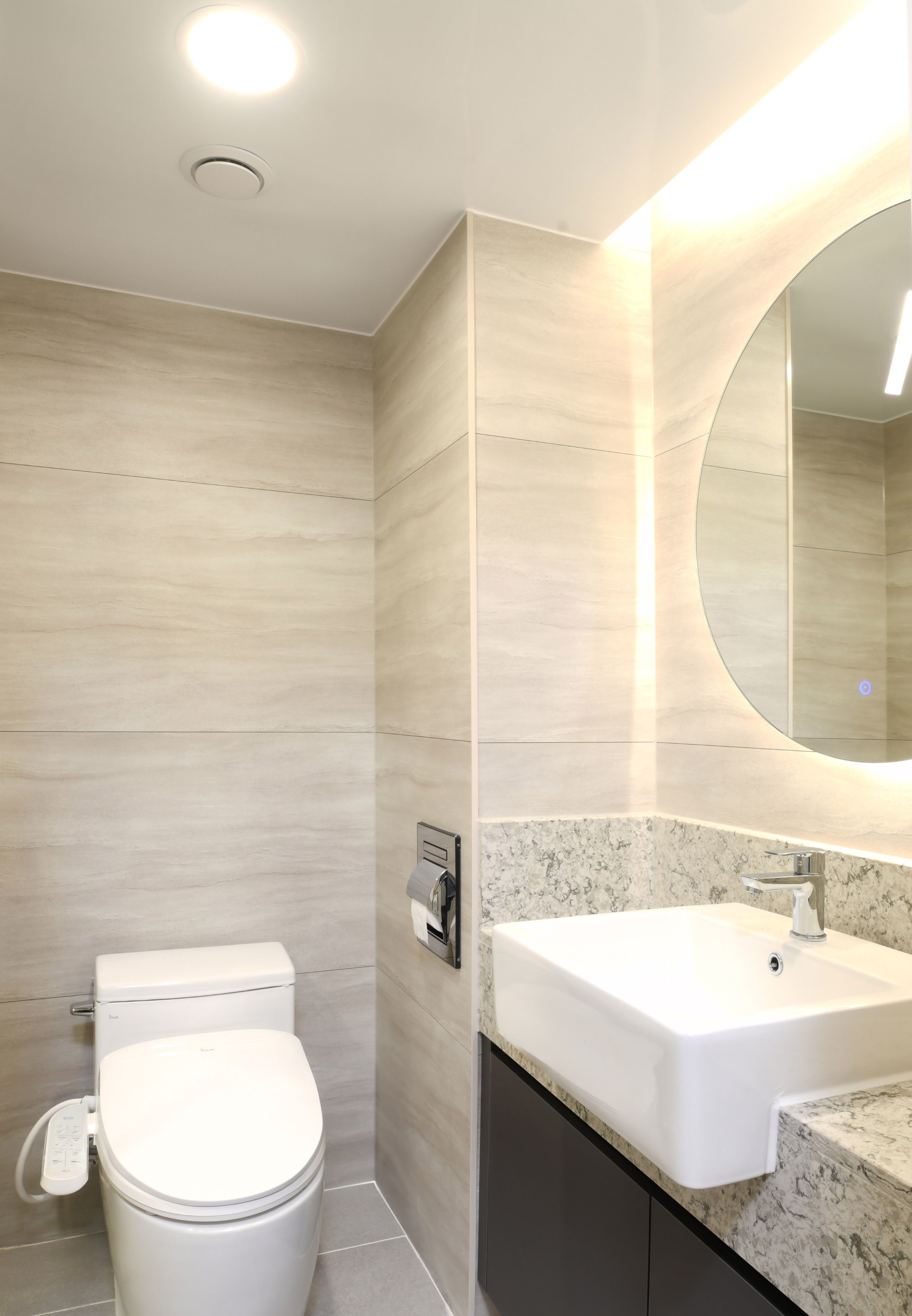 A modern bathroom with a toilet, sink, and mirror.