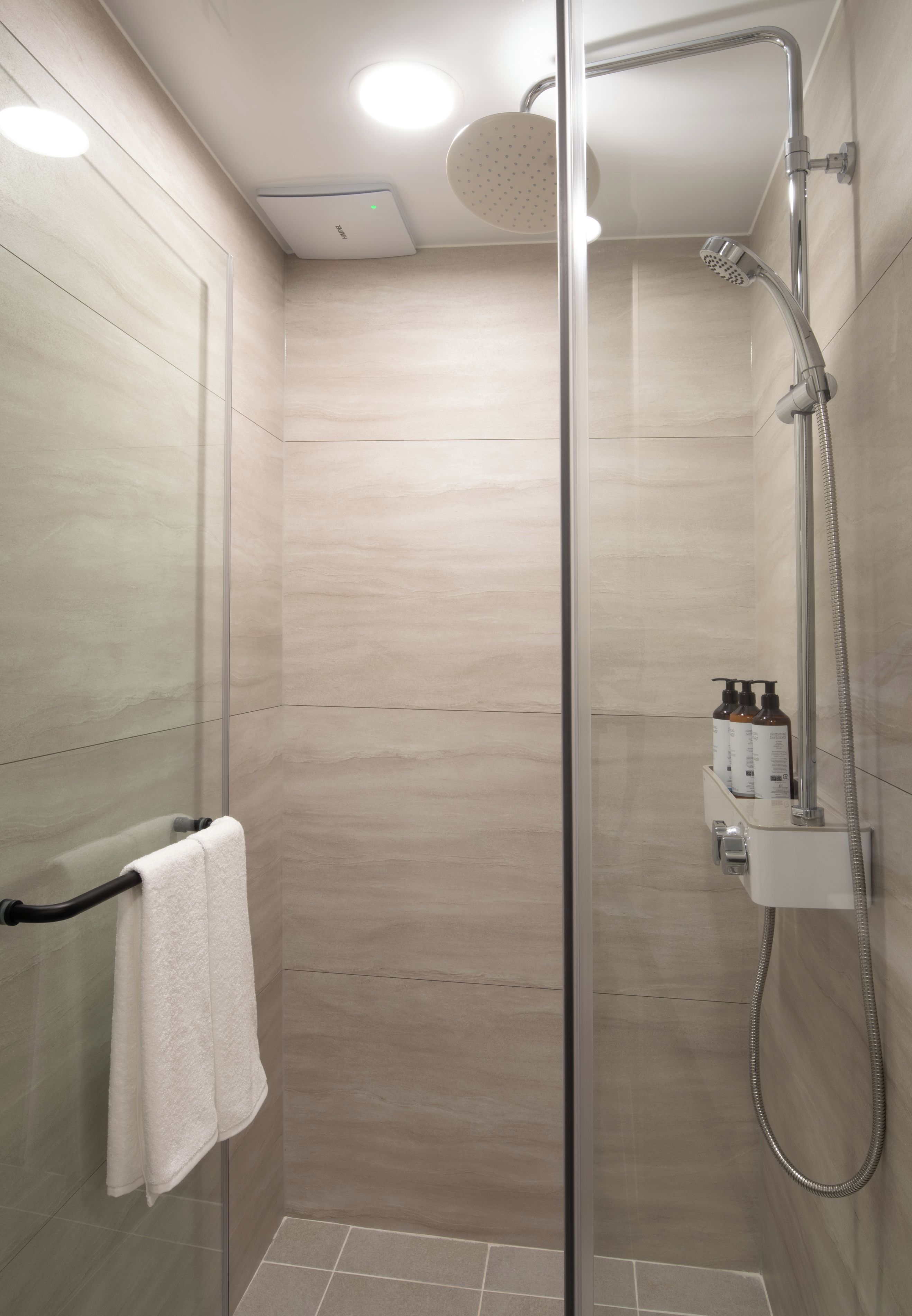 A modern shower with a handheld showerhead, a glass door, and a towel rack with a white towel.