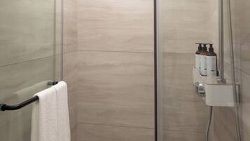 A modern shower with a handheld showerhead, a glass door, and a towel rack with a white towel.
