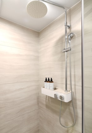 A shower with a handheld showerhead, a wall-mounted control panel, and a handheld shower hose. - Emerson Suites Naksan (Yangyang)