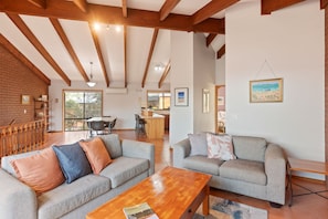 A spacious living area with two sofas, a wooden coffee table, and a kitchen in the background.