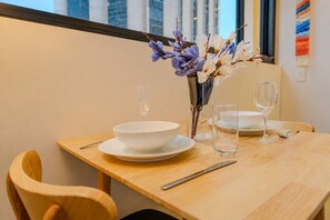 A dining table with a white bowl, two wine glasses, and a vase with flowers. - Stay in the Heart of Melbourne CBD-Walk Everywhere (Melbourne)