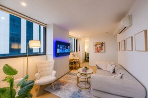 A modern living room with a flat-screen TV, a sofa, a chair, and a coffee table. - Stay in the Heart of Melbourne CBD-Walk Everywhere (Melbourne)