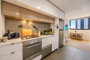 Una cocina moderna con estufa a gas, horno y un comedor con mesa y sillas.