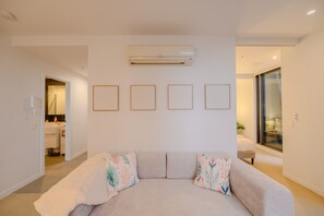 A modern living room with a sofa, a wall-mounted air conditioner, and framed artwork. - Stay in the Heart of Melbourne CBD-Walk Everywhere (Melbourne)