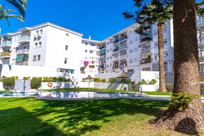 A residential building with multiple balconies, a swimming pool, and a well-maintained lawn. - Studio in Nerja Near Torrecilla Beach (Nerja)