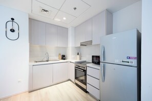 Eine moderne Küche mit weißen Schränken, einem Edelstahl-Kühlschrank, einem Einbauofen und einer Mikrowelle.