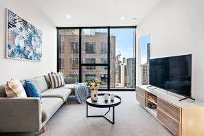 A modern living room with a sofa, coffee table, and a TV. - Cozy 2BR Apt | Vibrant Living w/ Pool & Gym (Melbourne)