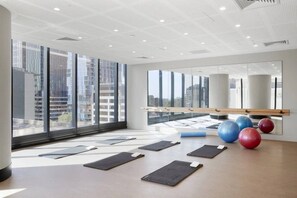 Ein geräumiges Zimmer mit großen Fenstern, einer Yoga-Matte und Trainingsbällen.
