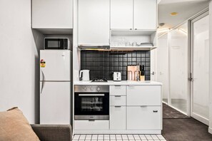Eine kompakte Küche mit Mikrowelle, Herd, Backofen und weißen Schränken.