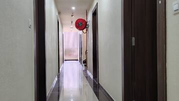 A hallway with a shiny floor, doors on both sides, and a red fire hose on the right.