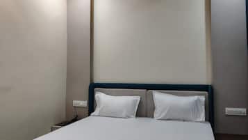 A hotel room with a bed, a ceiling fan, recessed lighting, and a nightstand.