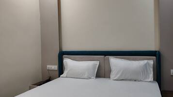A hotel room with a large bed, a nightstand, and a wall socket.