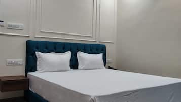 Un dormitorio con una cama grande, ropa de cama blanca, un cabecero tapizado en color aguamarina y suelo de mármol.