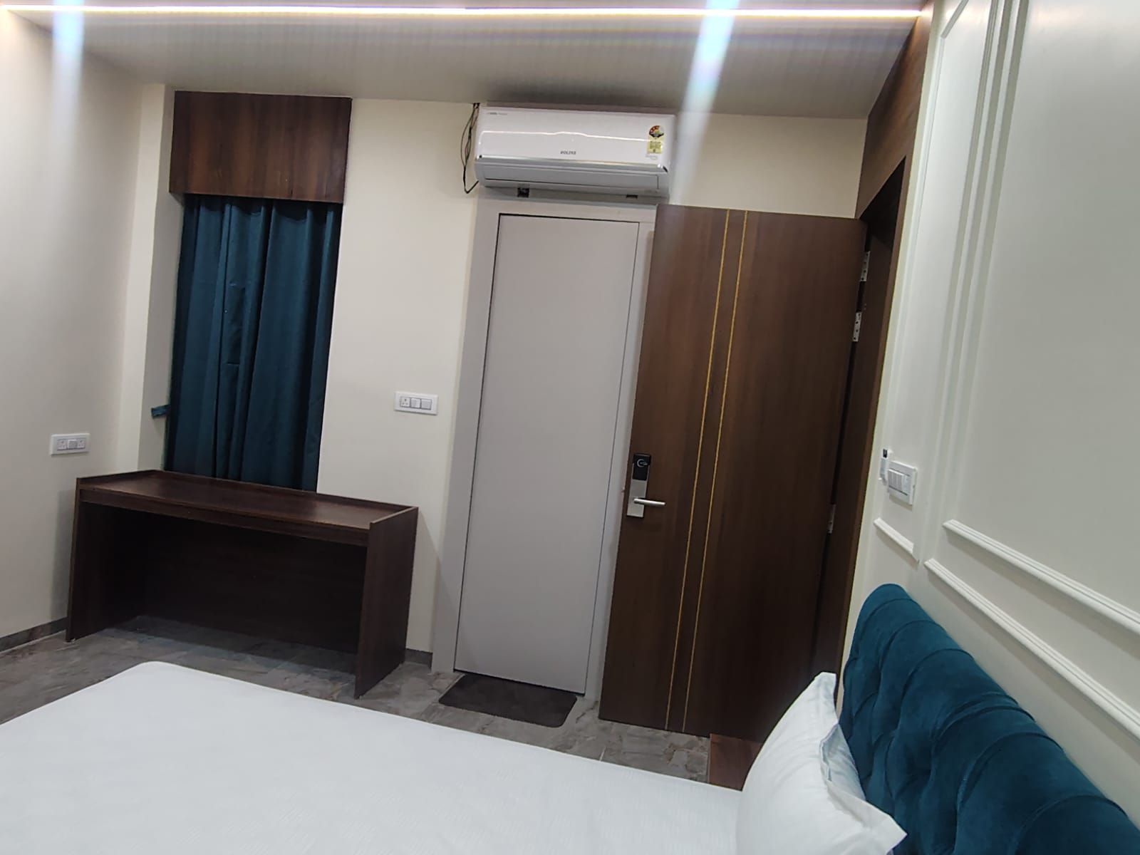 Een hotelkamer met een bed, een bureau, een kledingkast en een airconditioning.
