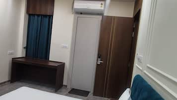 Een hotelkamer met een bed, een bureau, een kledingkast en een airconditioning.