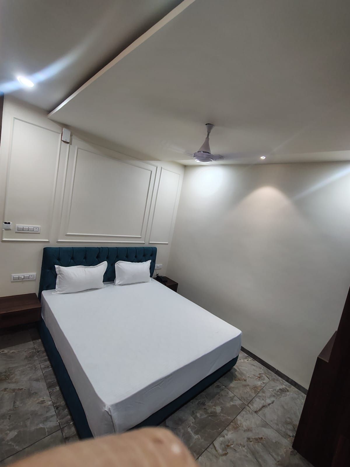 A bedroom with a bed, a ceiling fan, and a nightstand.