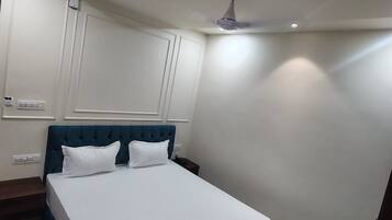 A bedroom with a bed, a ceiling fan, and a nightstand.