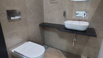 A modern bathroom with a toilet, a sink, and a mirror.