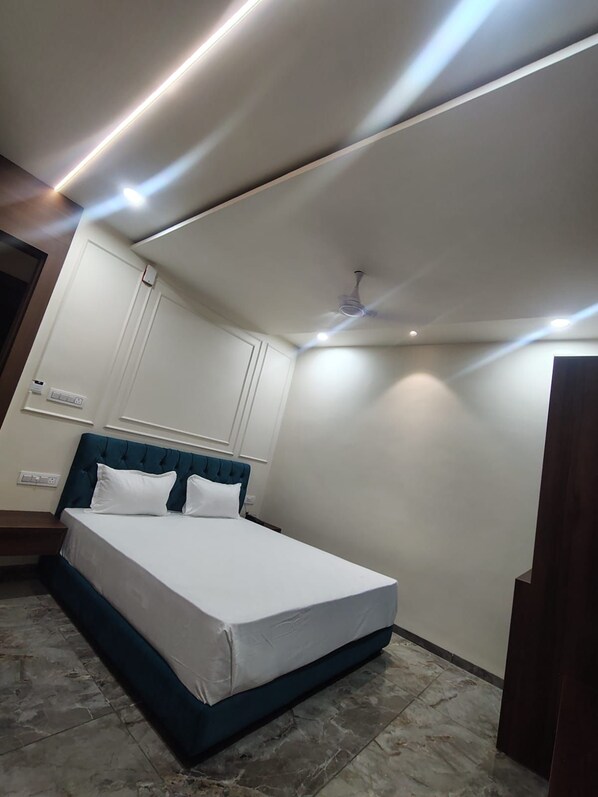 Un dormitorio con cama, ventilador de techo, luces empotradas y un armario blanco.