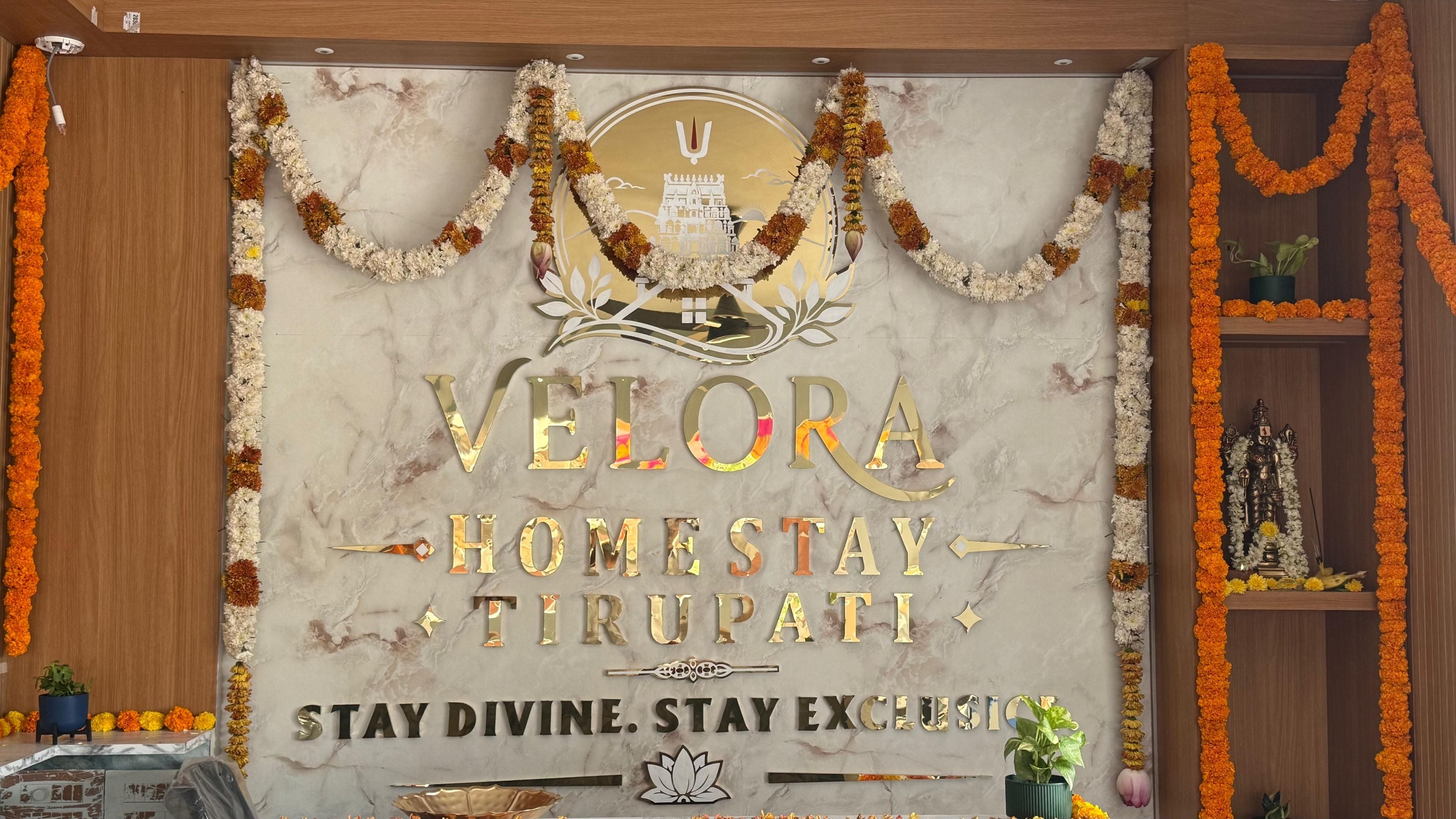 A marble wall with gold lettering and a central emblem, surrounded by floral garlands.