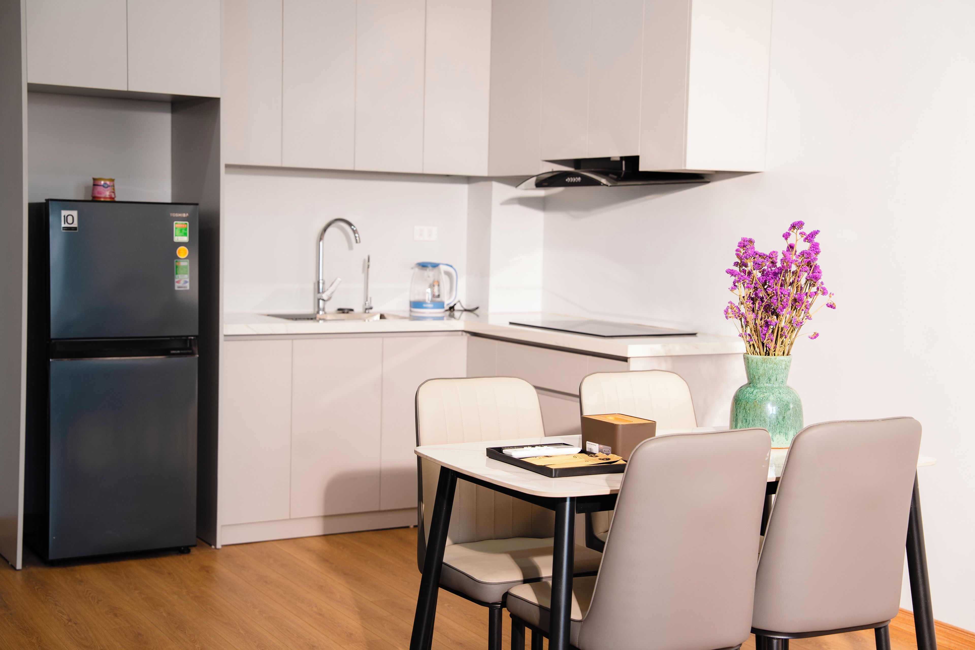 Una cocina moderna con refrigerador, lavamanos y comedor con sillas y mesa.